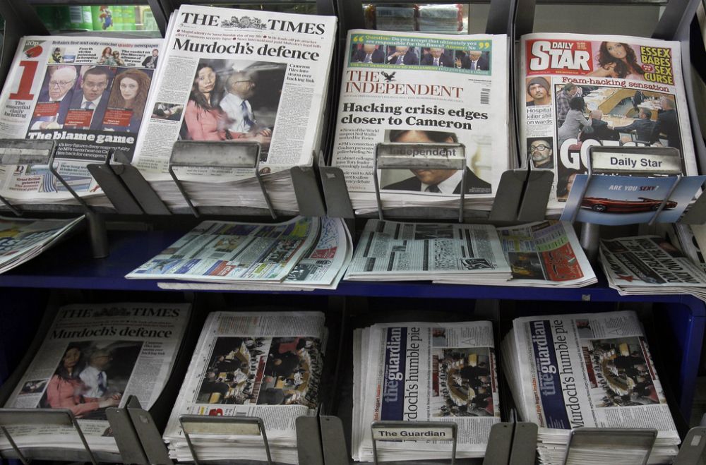 Newspapers for sale with headlines relating to the phone hacking scandal, near Westminster in London, Wednesday, July 20, 2011. Prime Minister David Cameron on Wednesday emphatically denied claims that his staff tried to stop an inquiry into phone hacking at the News of the World newspaper and defended his decision to hire one of the tabloid's editors as his communications chief.  (AP Photo/Kirsty Wigglesworth)