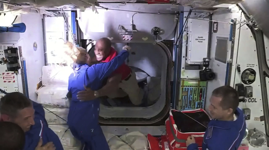 Retrouvailles chaleureuses entre les astronautes Victor Glover (au centre) et Kate Rubins (de dos) après l'arrimage de la capsule Dragon de SpaceX à la station spatiale internationale.