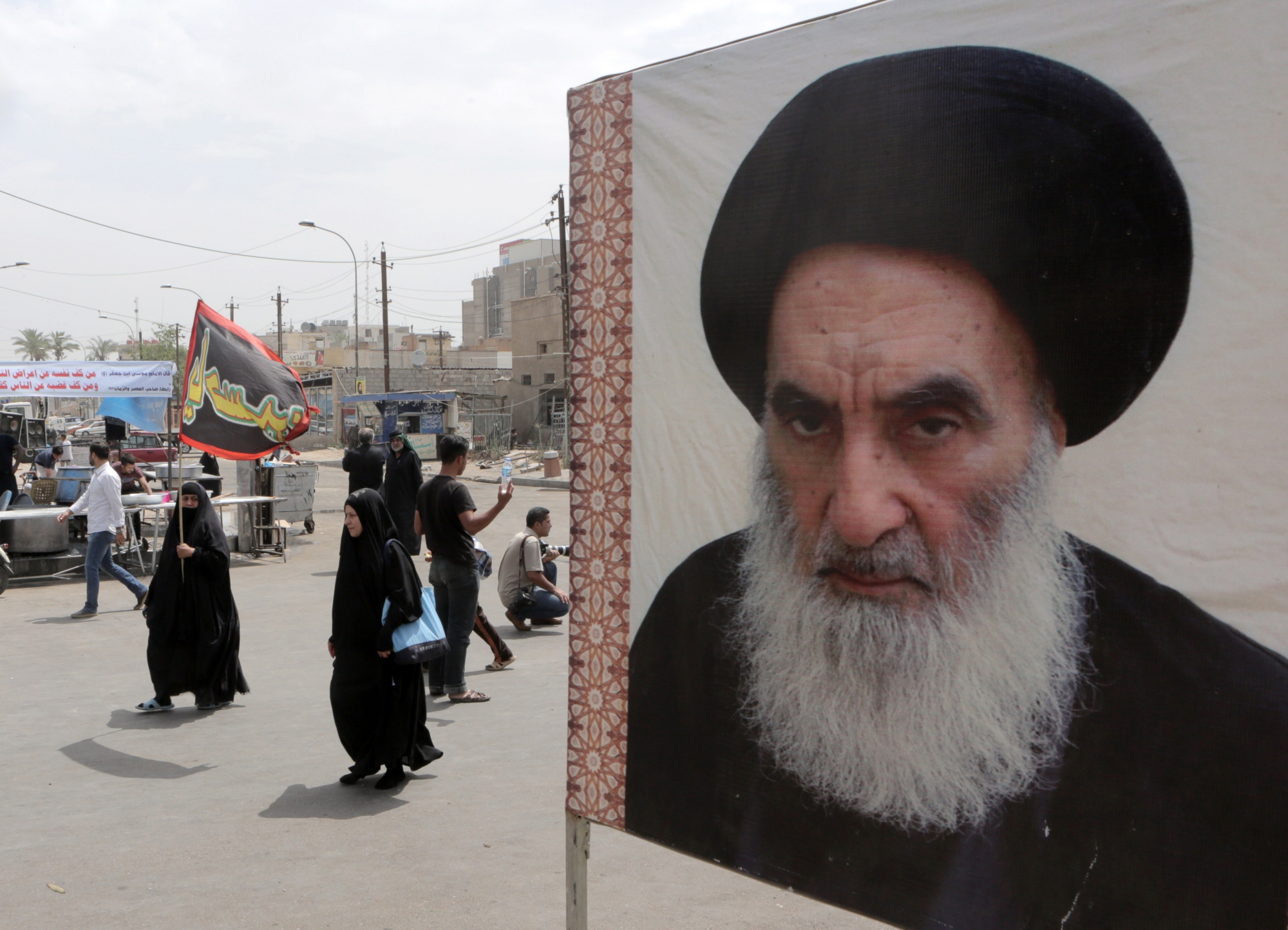 Shiite pilgrims make their way to the shrine of Imam Moussa al-Kadhim as passing by a poster of Shiite spiritual leader Grand Ayatollah Ali al-Sistani, right, in Baghdad, Iraq, Thursday, May 22, 2014. Shiite pilgrims are expected to converge on the shrine in northern Baghdad during their annual march to commemorate the eighth-century death of Imam Moussa al-Kadhim, a key Shiite saint. (AP Photo/Khalid Mohammed)