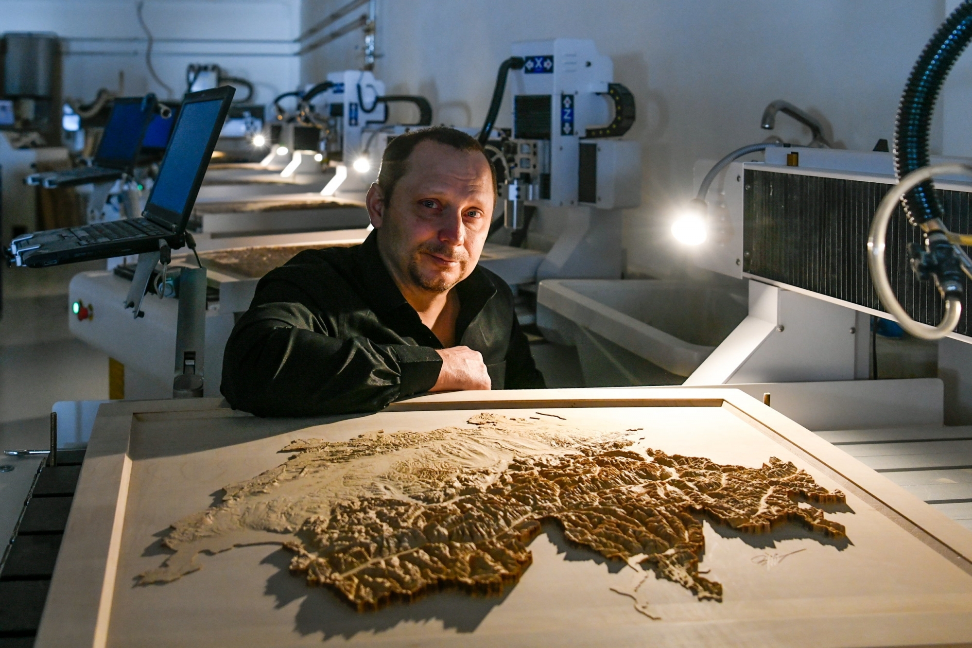 L'ingénieur Eric Marguet et une carte de la Suisse dont le relief a nécessité 240 heures de fraisage, soit 10 jours.