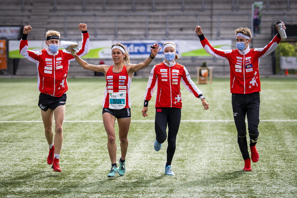 Les vainqueurs Joey Hadorn, Elena Roos, Simona Aebersold, Matthias Kyburz de Suisse célèbrent en franchissant la ligne d'arrivée lors de la course de relais sprint hommes et femmes aux Championnats d'Europe de course d'orientation à Neuchâtel.