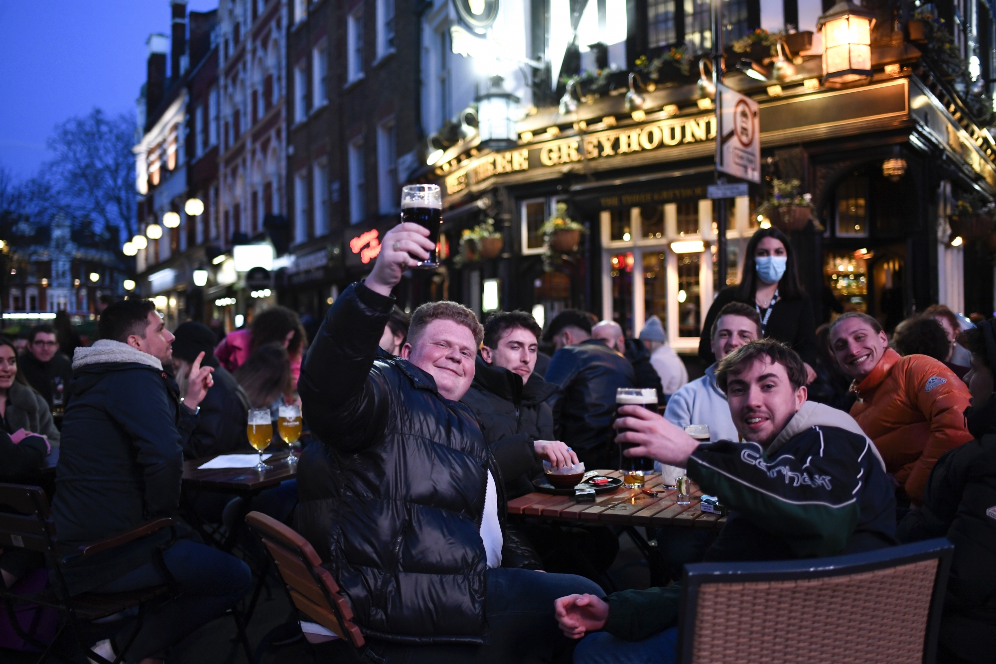 People sit at setup tables outside a pub in Soho, in London, on the day some of England's third coronavirus lockdown restrictions were eased by the British government, Monday, April 12, 2021. Pubs, shops and hairdressers have opened as lockdown restrictions are eased Monday. (AP Photo/Alberto Pezzali)