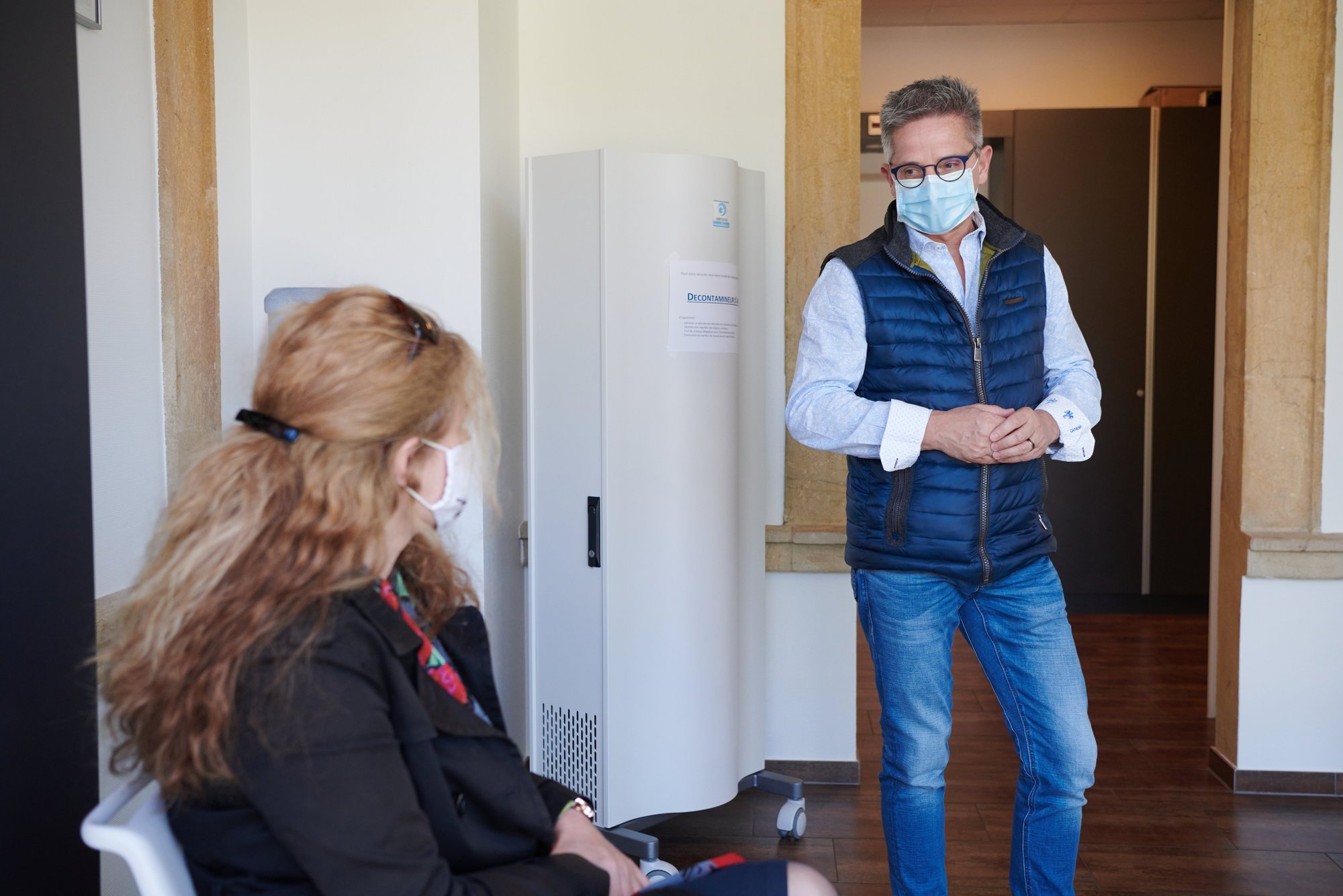 Le Dr Curty en discussion avec une patiente au Centre médical de La Côte, à Cormondrèche. En arrière-plan, le décontaminateur d'air.