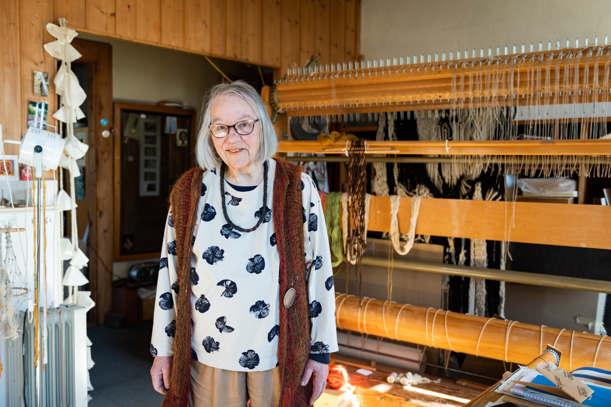 Jeanne-Odette devant son métier à tisser, outil de ses créations intemporelles et toujours modernes.