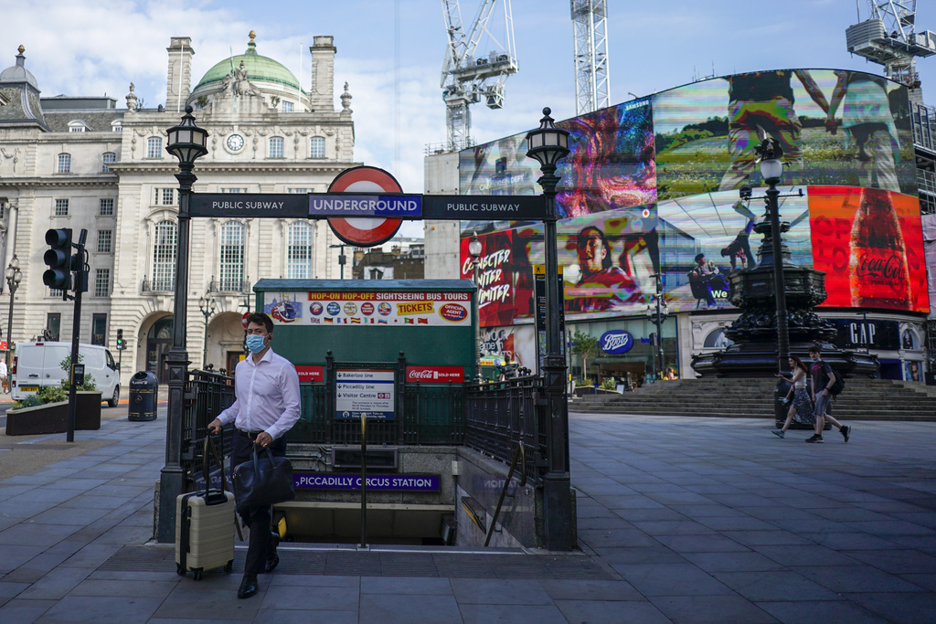 A man wears a face mask as he walks out from Piccadilly Circus station, in London, Monday, July 19, 2021. As of Monday, face masks are no longer legally required in England, and with social distancing rules shelved, there are no limits on the number of people attending theater performances or big events. (AP Photo/Alberto Pezzali)