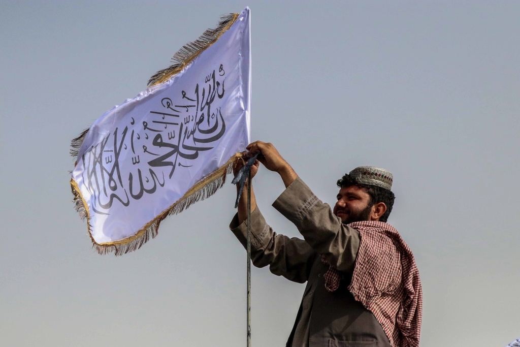 Un combattant taliban hisse son drapeau sur un véhicule alors qu'il patrouille à Kandahar, en Afghanistan.