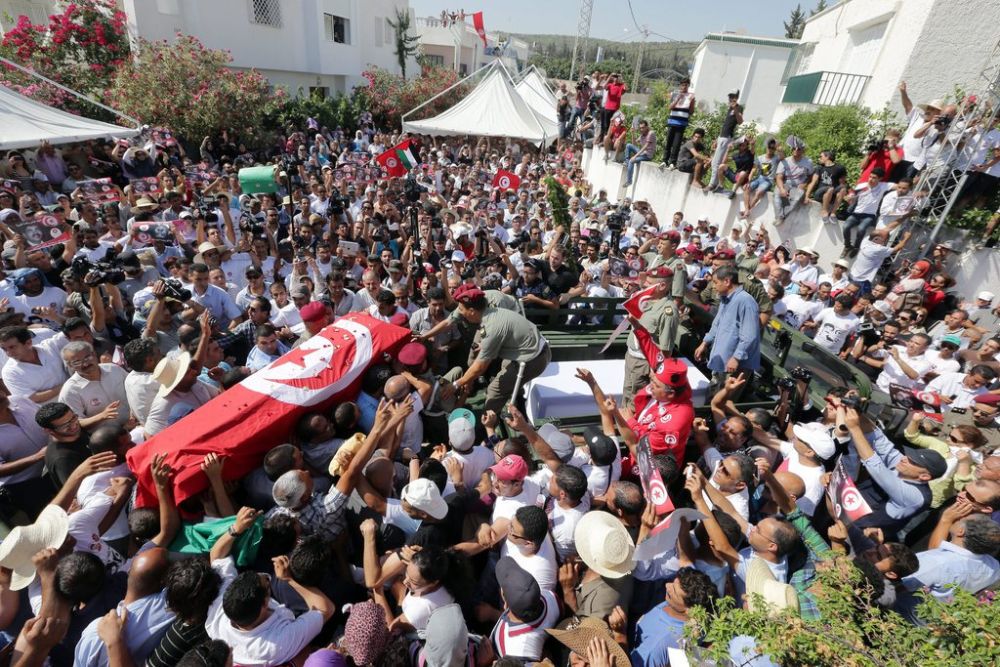 epa03803394 Tunisians carry the flag-draped coffin of slain opposition politician Mohamed Brahmi, during the funeral in Tunis, Tunisia, 27 July 2013. Brahmi was gunned down at his home in Tunis on 25 July 2013, the second such assassination this year in a country often praised as the most stable of Arab Spring countries. Authorities blamed Islamist radicals for his killing, saying he was shot with the same weapon used to kill Chokri Belaid, an opposition leader assassinated half a year ago.  EPA/MOHAMED MESSARA