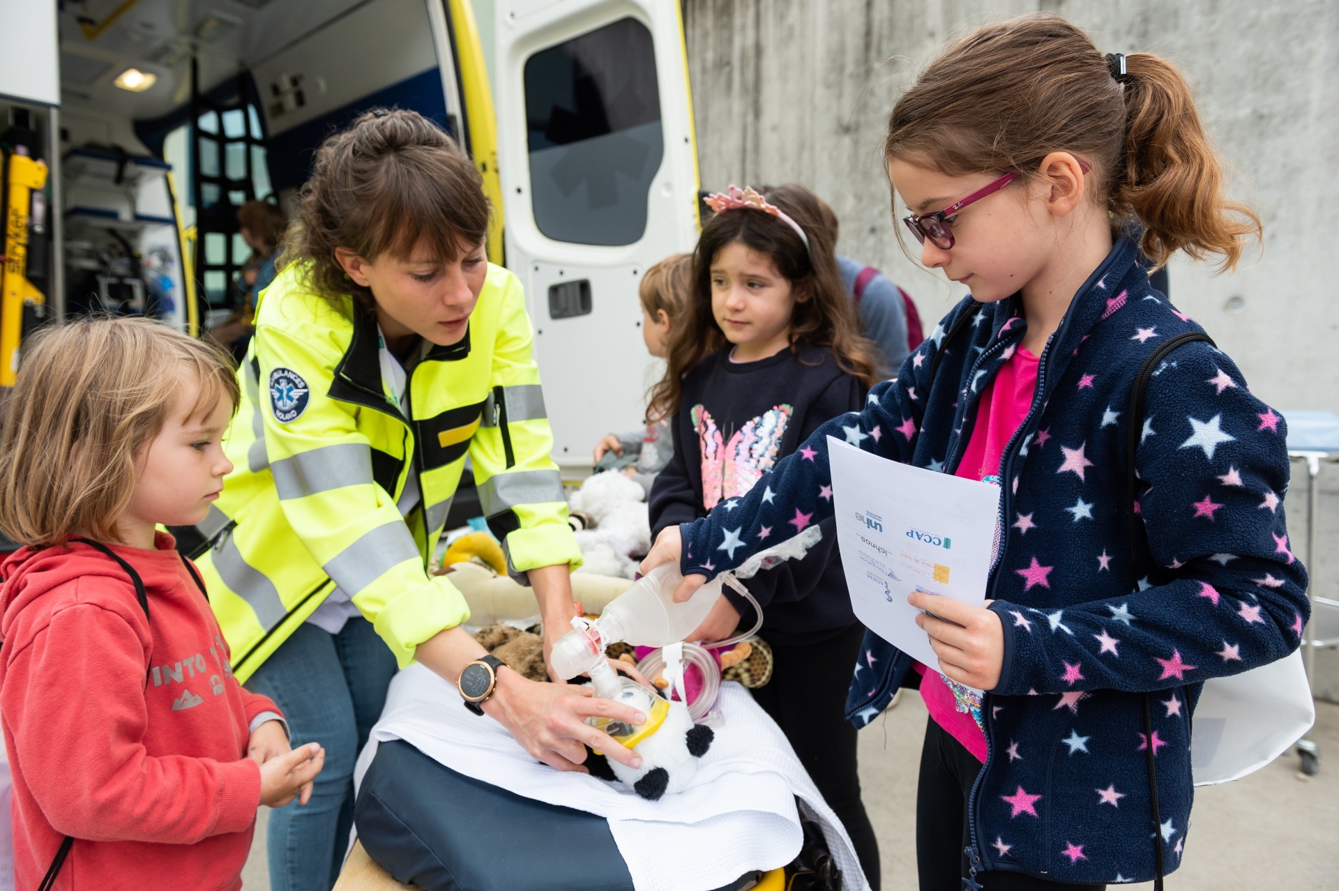 L'ambulancière est en train de me donner de l'oxygène sur le brancard. Tout à droite de l'image, mon amie Malou.