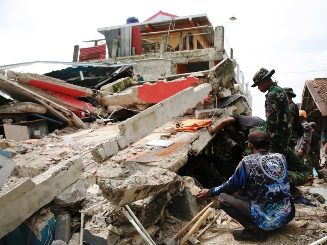 Des militaires et des secouristes indonésiens recherchent des victimes dans une maison effondrée, à Cianjur.