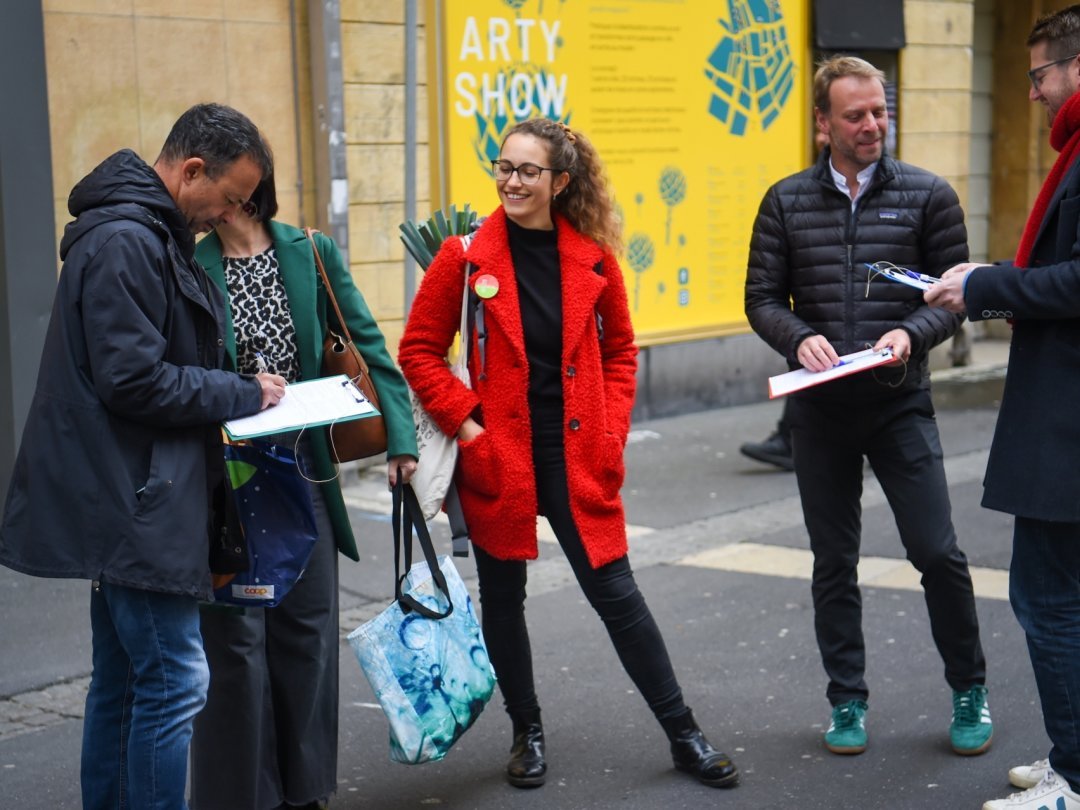 Des passants signent l'initiative en ville de Neuchâtel, en présence des Verts Cloé Dutoit et  Fabien Fivaz et du socialiste Baptiste Hurni (de gauche à droite).