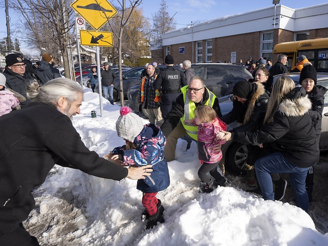 Des parents et leurs enfants sont embarqués dans un bus de secours alors qu'ils attendent des nouvelles après qu'un bus a percuté une crèche à Laval, au Québec, mercredi. KEYSTONE/AP/Ryan Remiorz