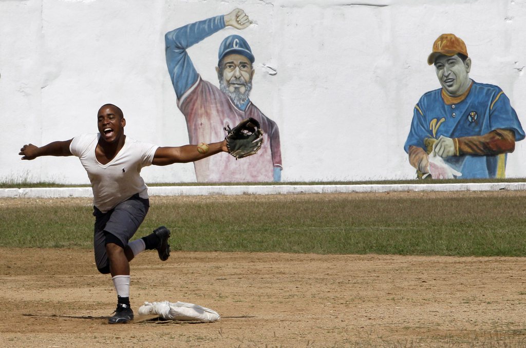 A prisoner plays baseball at the Combinado del Este prison, where a mural of Cuban leader Fidel Castro and Venezuela's late President Hugo Chavez cover a wall, during a media tour of the prison in Havana, Cuba, Tuesday, April 9, 2013.  Cuban authorities led foreign journalists through the maximum security prison, the largest in the Caribbean country that houses 3,000 prisoners. Cuba says they have 200 prisons across the country, including five that are maximum security. (AP Photo/Franklin Reyes)