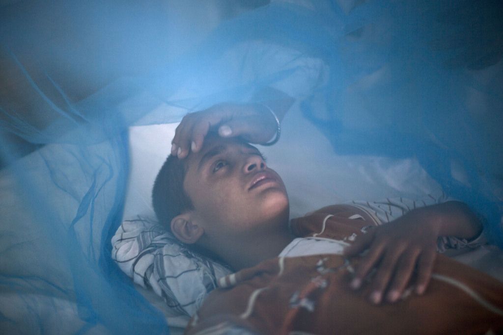 Pakistani boy, Awais Shaukat, 13, suffering from the mosquito-borne disease, dengue fever, is comforted by his father Shaukat while lying in bed covered with a net at an isolation ward of a hospital in Rawalpindi, Pakistan, Thursday, Oct. 24, 2013. Dengue, a flu-like illness, is spread by the Aedes mosquito and spikes during the annual monsoons in Pakistan, when the rains leave puddles of stagnant water where the insects breed. (AP Photo/Muhammed Muheisen)