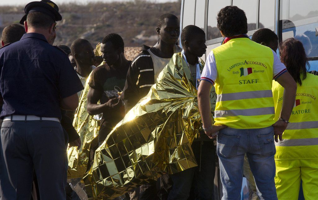 Migrants are assisted as they arrive in the port of the island of Lampedusa southern Italy, Monday July 8, 2013. Pope Francis has arrived on the tiny Sicilian island of Lampedusa to greet recently arrived migrants as yet another boatload came ashore carrying 162 Eritreans. Francis came to pray with survivors of the treacherous crossing from Africa and mourn those who have died trying. He flew Monday from Rome to Lampedusa's airport and was traveling by coast guard ship to the island's main port, where he is to throw a wreath of flowers into the sea to remember migrants who never arrived. (AP Photo/Alessandra Tarantino)