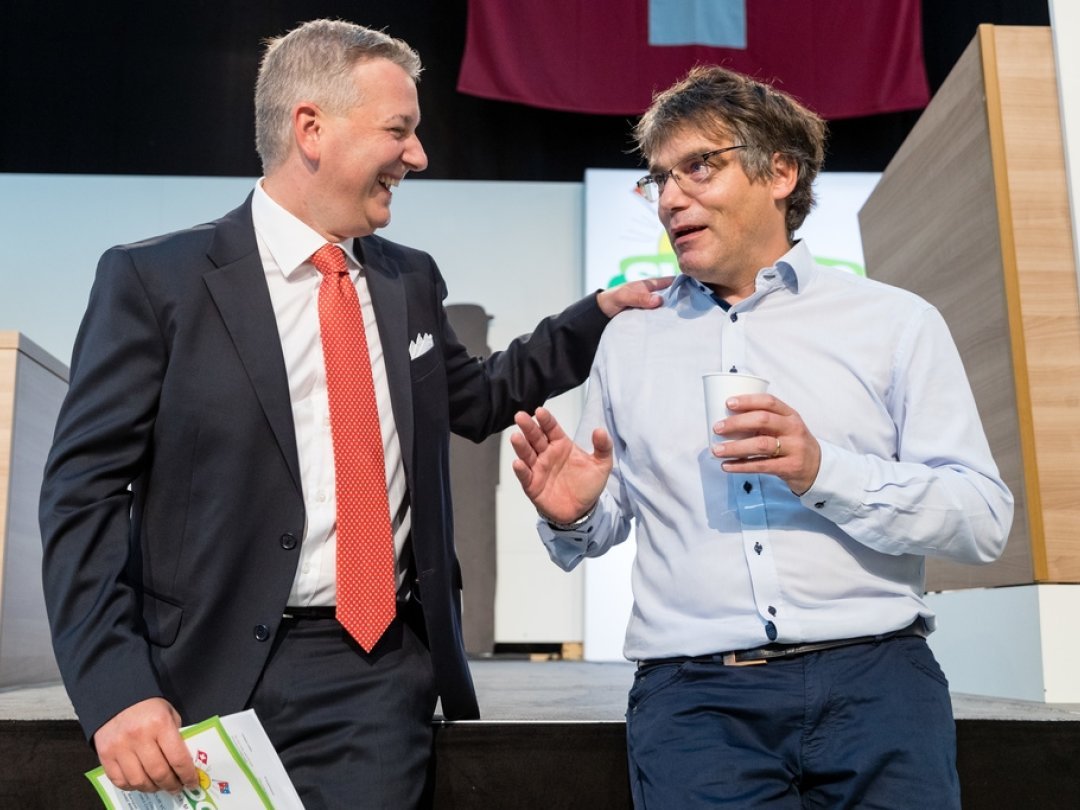 Le socialiste Roger Nordmann (à droite) et le président de l'UDC lors de l'assemblée des délégués du parti agrarien, le 20 août 2022, à Baar (ZG).