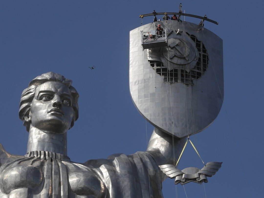 Des ouvriers enlèvent les armoiries de l’ancienne Union soviétique du Mémorial de la Seconde Guerre mondiale à Kiev.