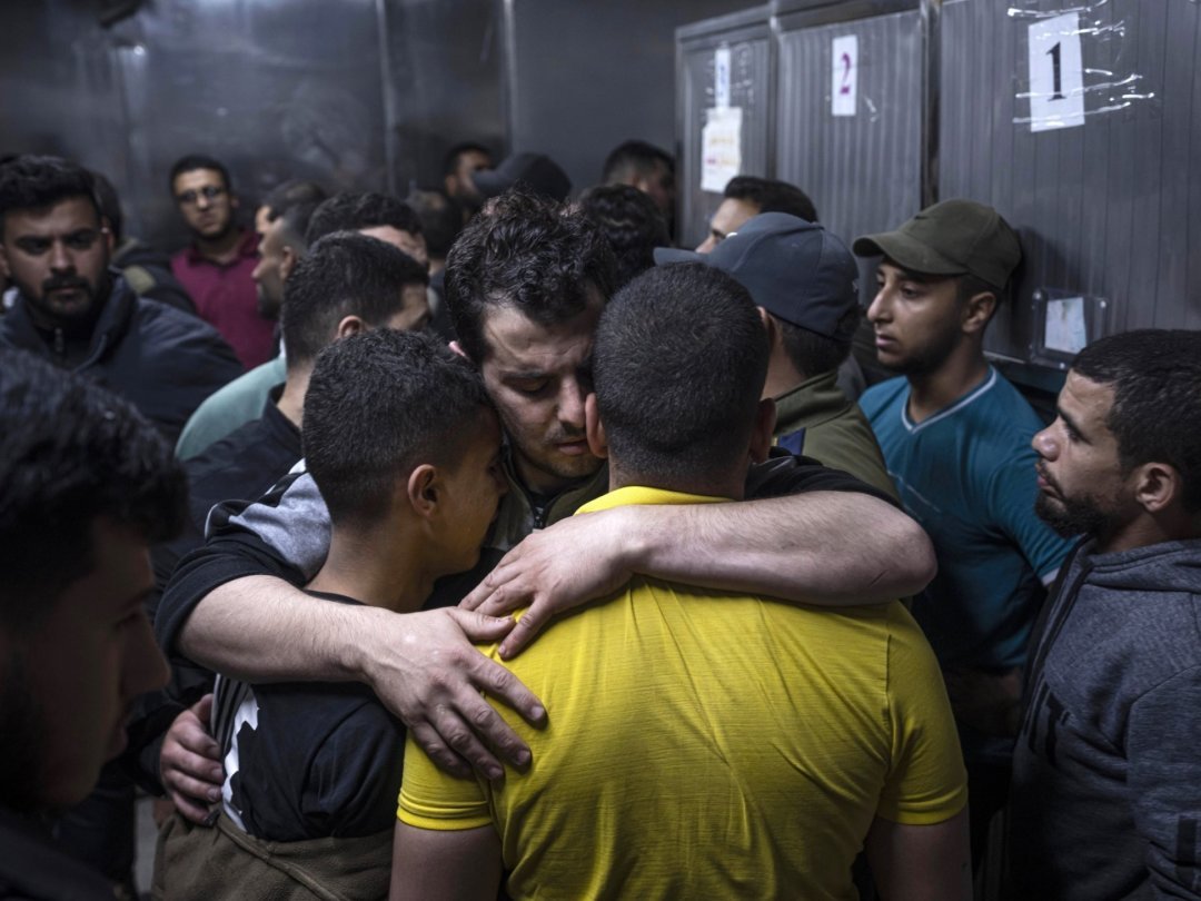 Gaza, jeudi 12 octobre 2023. Des personnes en deuil se réconfortent dans la morgue d'un hôpital après que des frappes aériennes israéliennes ont tué une douzaine de Palestiniens.