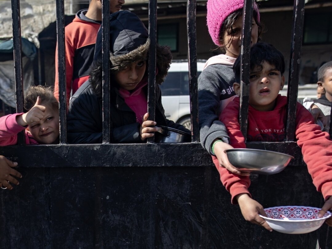 Des enfants palestiniens déplacés font la queue pour récupérer un peu de nourriture, dans un camp de réfugiés de Rafah dans la bande de Gaza, le 1 février 2024.