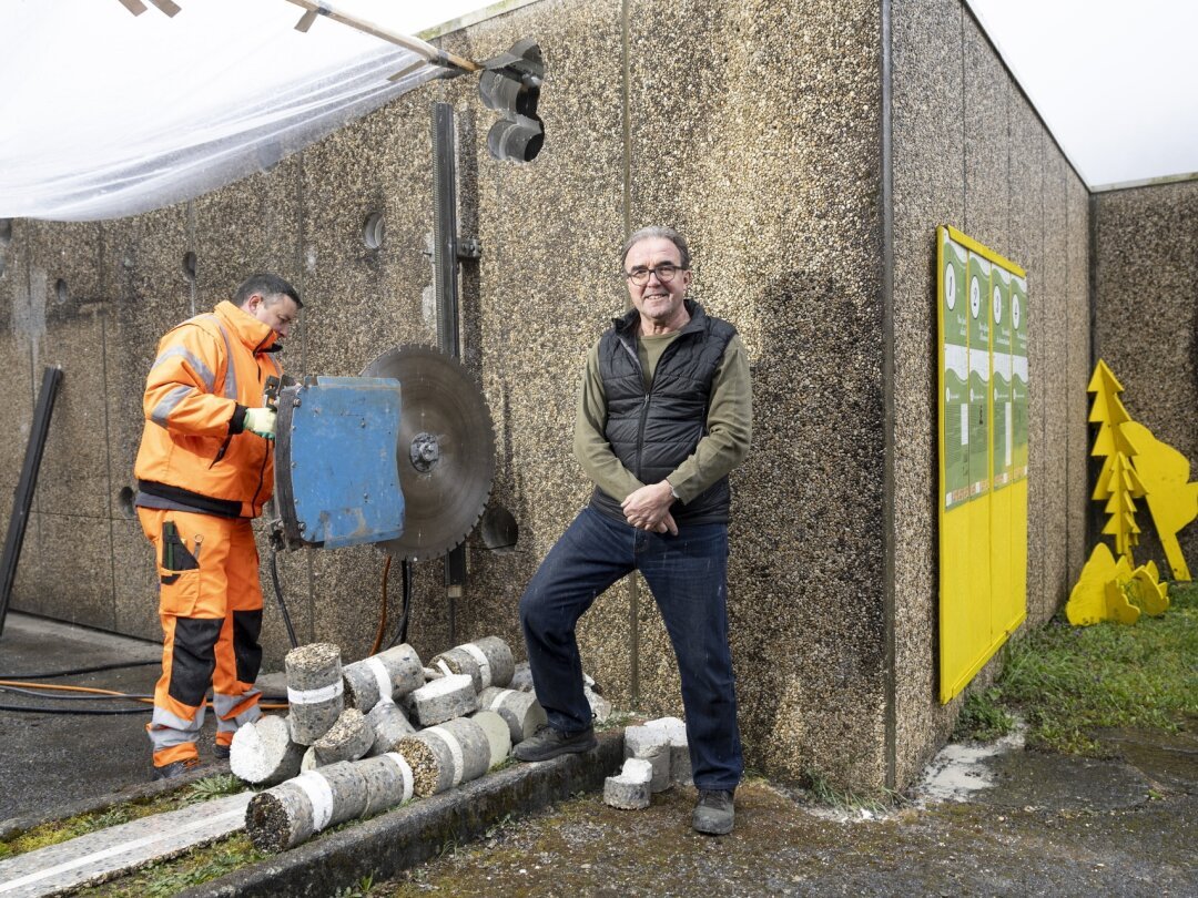 Daniel Huguenin-Dumittan pose à côté de l'ouvrier en train de scier la structure en béton où sera installée une grande baie vitrée.