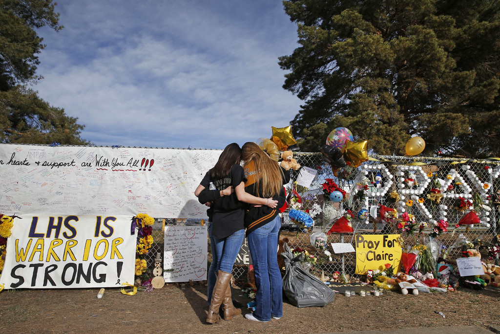 Arapahoe High School students hug at a tribute site for severely wounded student Claire Davis, who was shot by a classmate during a school attack six days earlier at Arapahoe High School, in Centennial, Colo., Thursday Dec. 19, 2013. On Thursday, students were allowed back into school to retrieve their belongings. (AP Photo/Brennan Linsley)