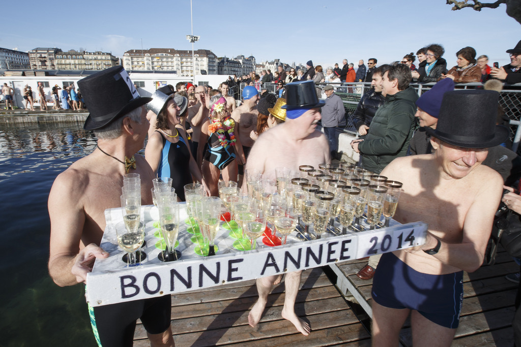 Mens in swimsuits carry a tray with glasses of champagne, prior the annual swim in the Lake of Geneva for celebrating the New Year at the Bains des Paquis, in Geneva, Switzerland, Wednesday, January 1, 2014. (KEYSTONE/Salvatore Di Nolfi)