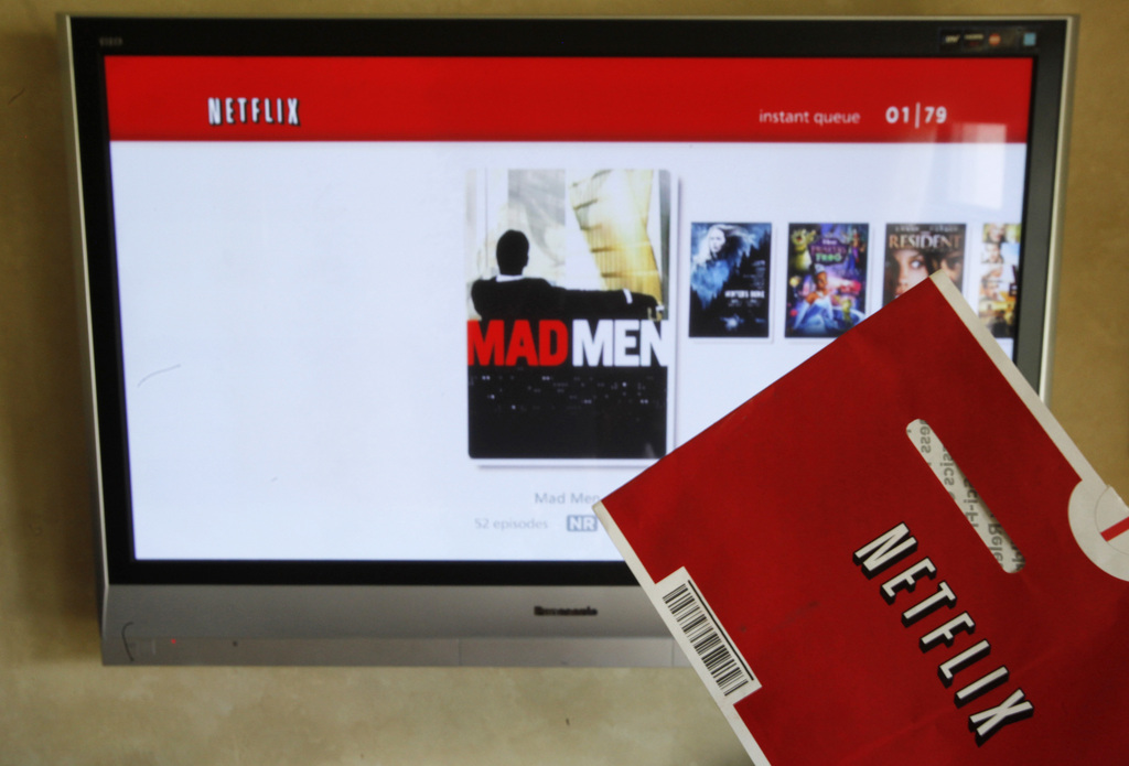 In this Oct. 1, 2011 photo, a Netflix DVD envelope and Netflix on-screen television menu are shown in Surfside, Fla. Netflix's CEO says it's abandoning its widely panned decision to separate its DVD-by-mail and Internet streaming accounts.(AP Photo/Wilfredo Lee)