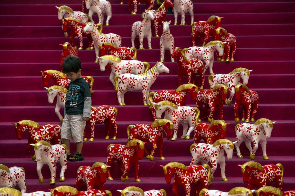 epa04037648 A boy walks among small horse statues that adorn a shopping mall for the upcoming Chinese New Year of the horse in Kuala Lumpur, Malaysia, 23 January 2014. The Chinese New Year of the horse begins on 31 January 2014.  EPA/AHMAD YUSNI