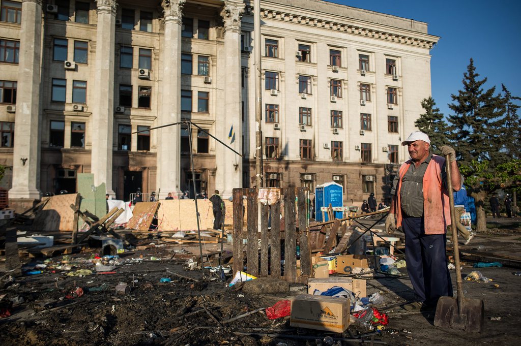 epa04189550 A cleaner looks at the remains of the destroyed pro-Russian protester's camp near the Trade Union building in the South-Ukrainian city of Odessa, Ukraine, 03 May 2014. At least 31 people died in a fire that broke out during clashes between pro-Ukrainian and pro-Russian protesters at the Trade Union building in Odessa. Apart from the fire death toll, the fighting left at four people dead and 40 injured, police said.  EPA/ALEXEY FURMAN