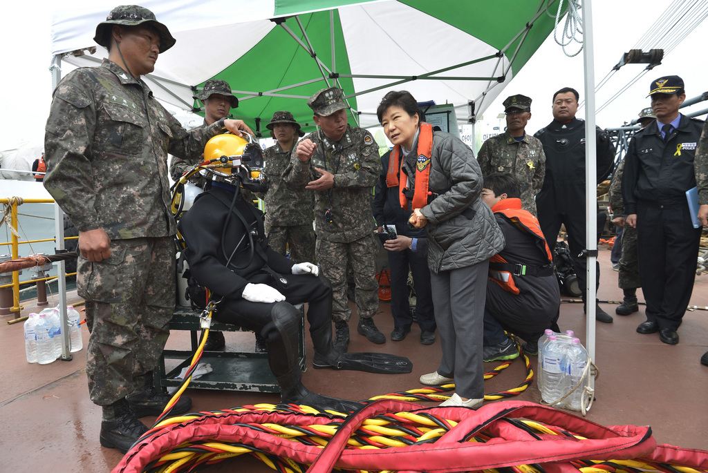 South Korean President Park Geun-hye, center, talks with a diver at the site where the ferry Sewol sank in waters off the southern coast near Jindo, South Korea, Sunday, May 4, 2014. Park told families of those missing in the sunken ferry that her heart breaks knowing what they are going through, as divers recovered two more bodies on Sunday. (AP Photo/Yonhap)  KOREA OUT