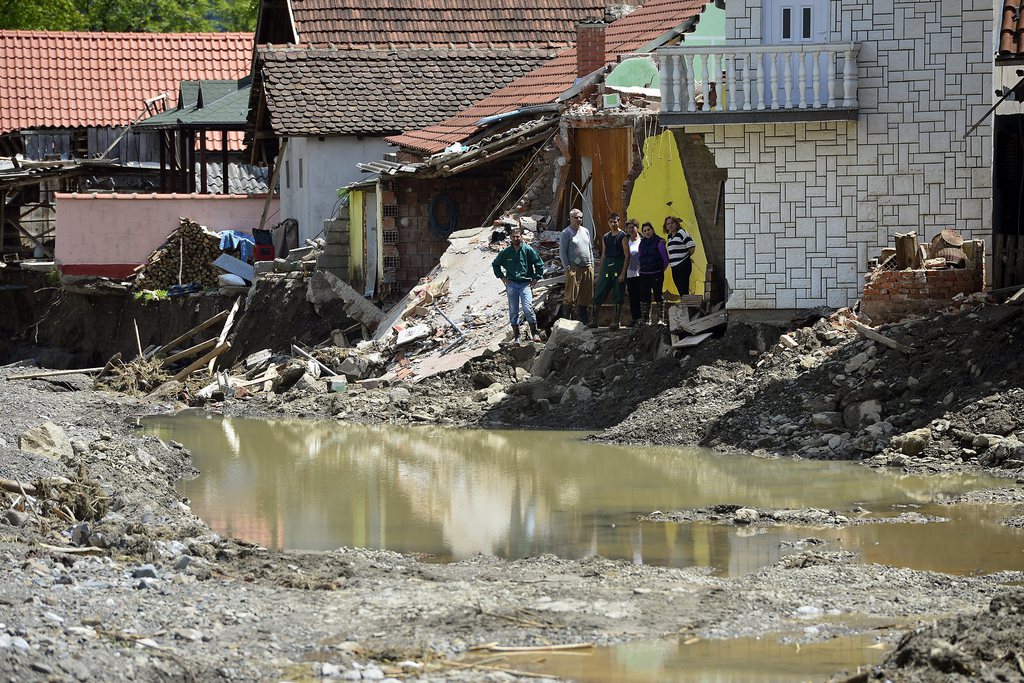 epa04214672 A picture made available on 19 May 2014 shows residents standing in the damage suffered by all the houses in the upper part Krupanj, Serbia, 18 May 2014. The death toll from flooding in the Balkans rose to 40 on 19 May as emergency services in Bosnia, Croatia and Serbia struggled to house those displaced, reinforce dykes on swollen rivers and begin a massive clean-up operation. In Serbia, more casualties were confirmed since 14 May. Thirteen of the 20 victims drowned in Obrenovac, a Belgrade borough that has been hardest-hit over the last week. The Serbian Interior Ministry ordered a full evacuation of Obrenovac as the level of the river Sava is expected to rise. Emergency Situations Ministry and fire services evacuated hundreds of residents by helicopter, trucks, bulldozers and boat from Obrenovac.  EPA/NEMANJA JOVANOVIC