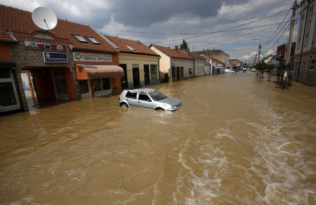 Destroyed car stand in water in a flooded street in Obrenovac, some 30 kilometers (18 miles) southwest of Belgrade, Serbia, Tuesday, May 20, 2014. Serbia,  At least 34 people have died and tens of thousands evacuated in Serbia and Bosnia as the emergency services fought with overflowing of rivers and growing landslides following worst floods in a century. (AP Photo/Darko Vojinovic)