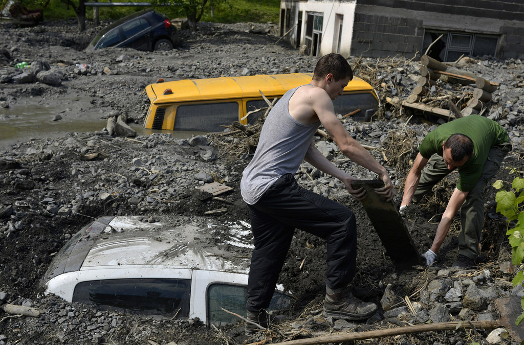Residents try to excavate a car trapped in the mud caused by a landslide at the village of Topcic Polje, near the Bosnian town of Zenica, 90 kilometers north of Sarajevo, Bosnia-Herzegovina Tuesday May 20, 2014. Bosnia, Serbia and Croatia have been hit by the worst flooding in more than 100 years, forcing half a million people out of their homes and leading to more than three dozen deaths. (AP Photo/Sulejman Omerbasic)