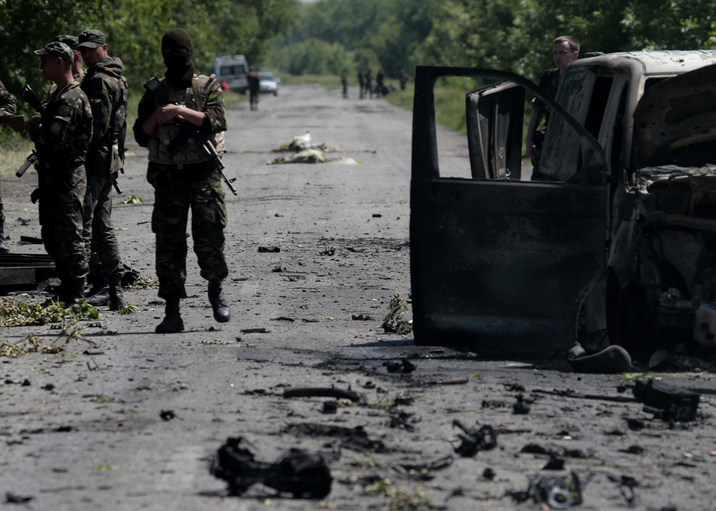 An Ukrainian soldier walks at a gunfight site near the village of Blahodatne, eastern Ukraine, on Thursday, May 22, 2014. At least 11 Ukrainian troops were killed and about 30 others were wounded when Pro-Russians attacked a military checkpoint, the deadliest raid in the weeks of fighting in eastern Ukraine. Three charred Ukrainian armored infantry vehicles, their turrets blown away by powerful explosions, and several burned vehicles stood at the site of the combat. (AP Photo/Ivan Sekretarev)