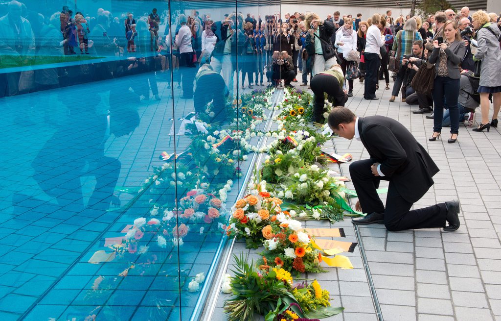 epa04380751 Visitors lay flowers against the blue glass wall at the memorial for the victims of the National Socialist euthanasia killings at its inauguration in Berlin, Germany, 2 September 2014. The central organization office, responsible for the coordination and excecution of mass killings of sanatoria and convalescent homes patients, was located in Berlin, Tiergartenstrasse.  EPA/SOEREN STACHE