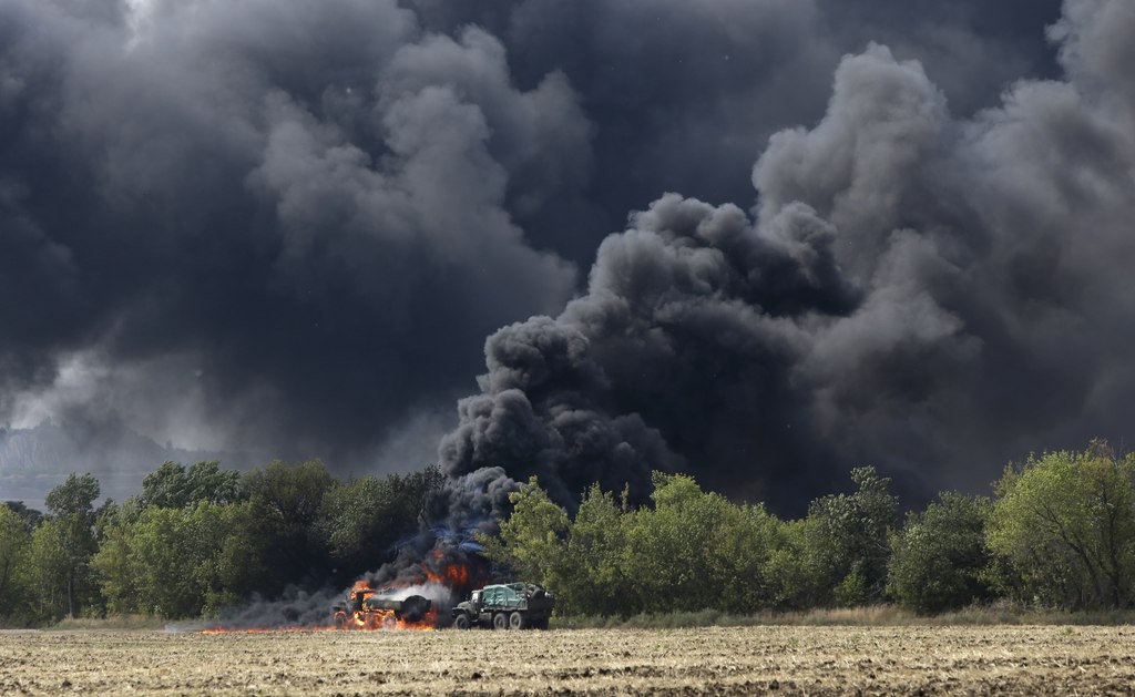 Unmarked military vehicles burn on a country road in the village of Berezove, eastern Ukraine, Thursday, Sept. 4, 2014, after a clash between pro-government troops and Russian-backed separatist militia. Separatist rebels have made major strides in their offensive against Ukrainian government forces in recent days, drawing on what Ukraine and NATO says is ample support from the Russian military. (AP Photo/Sergei Grits)
