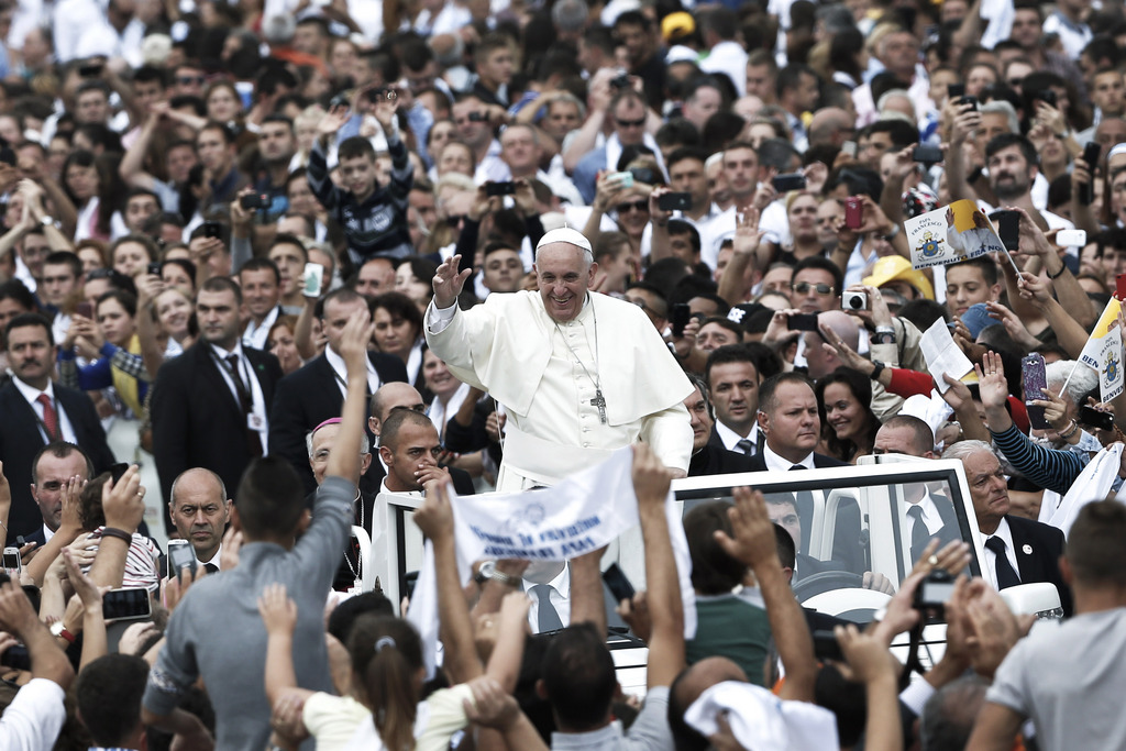 Pope Francis waves to faithful as he is driven through the crowd, in Mother Teresa Square, in Tirana, Sunday, Sept. 21, 2014. Pope Francis arrived Sunday in Albania on his first European trip, designed to highlight the Balkan nation's path from a brutal communist state where religion was banned to a model of Christian-Muslim coexistence for a world witnessing conflict in God's name. (AP Photo/Petros Giannakouris)