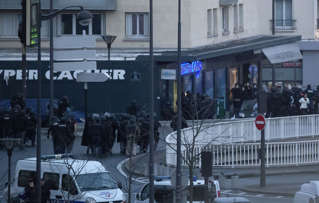French police officers storm a kosher grocery to end a hostage situation, Paris, Friday, Jan. 9, 2015. Explosions and gunshots were heard as police forces stormed a kosher grocery in Paris where a gunman was holding at least five people hostage. (AP Photo/Michel Euler)