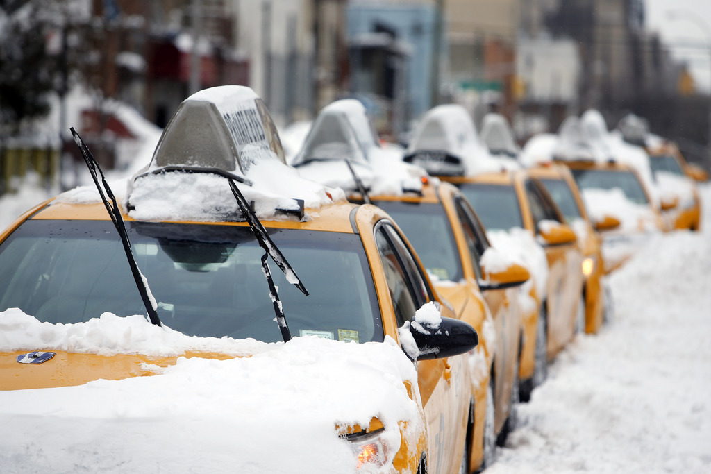 Taxis that belong to Arthur Cab Leasing Corp.,  stand idle outside the company's lot before being put it back into service following a winter storm, Tuesday, Jan. 27, 2015, in the Queens borough of New York.  Manager Shaon Chowdhury estimates that the winter storm has cost his company approximately $60,000 in lost revenue and added expenses. (AP Photo/Jason DeCrow)