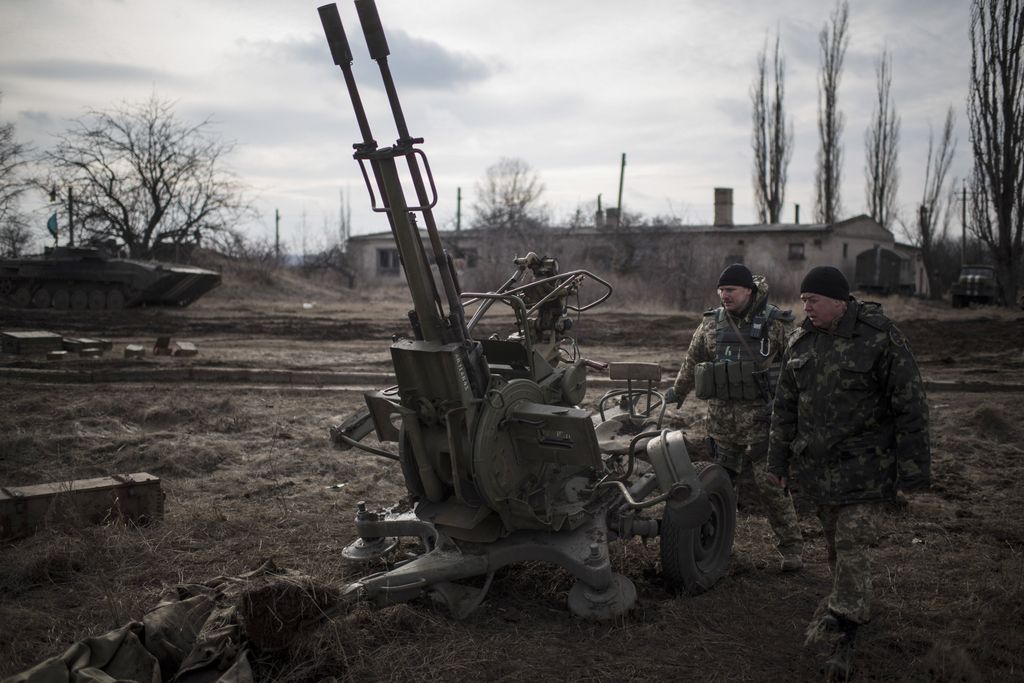 Ukrainian soldiers walk past weapons near Debaltseve, eastern Ukraine, Sunday, Feb. 8, 2015. The government-held town of Debaltseve, a key railway junction, has been the epicenter of recent battles between Russian-backed separatists and Ukrainian government troops. For two weeks, the town has been pounded by intense shelling that knocked out power, heat and running water in the dead of winter. (AP Photo/Evgeniy Maloletka)