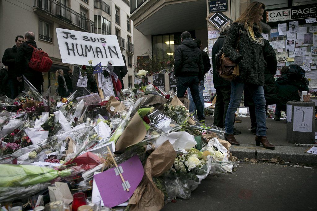 epa04557227 People gather and pay their respects next to the 'Charlie Hebdo' offices in Paris, France, 12 January 2015. Three days of terror that ended on 10 January saw 17 people killed in attacks that began with gunmen invading French satirical magazine Charlie Hebdo and continued with the shooting of a policewoman and the siege of a Jewish supermarket.  EPA/ETIENNE LAURENT