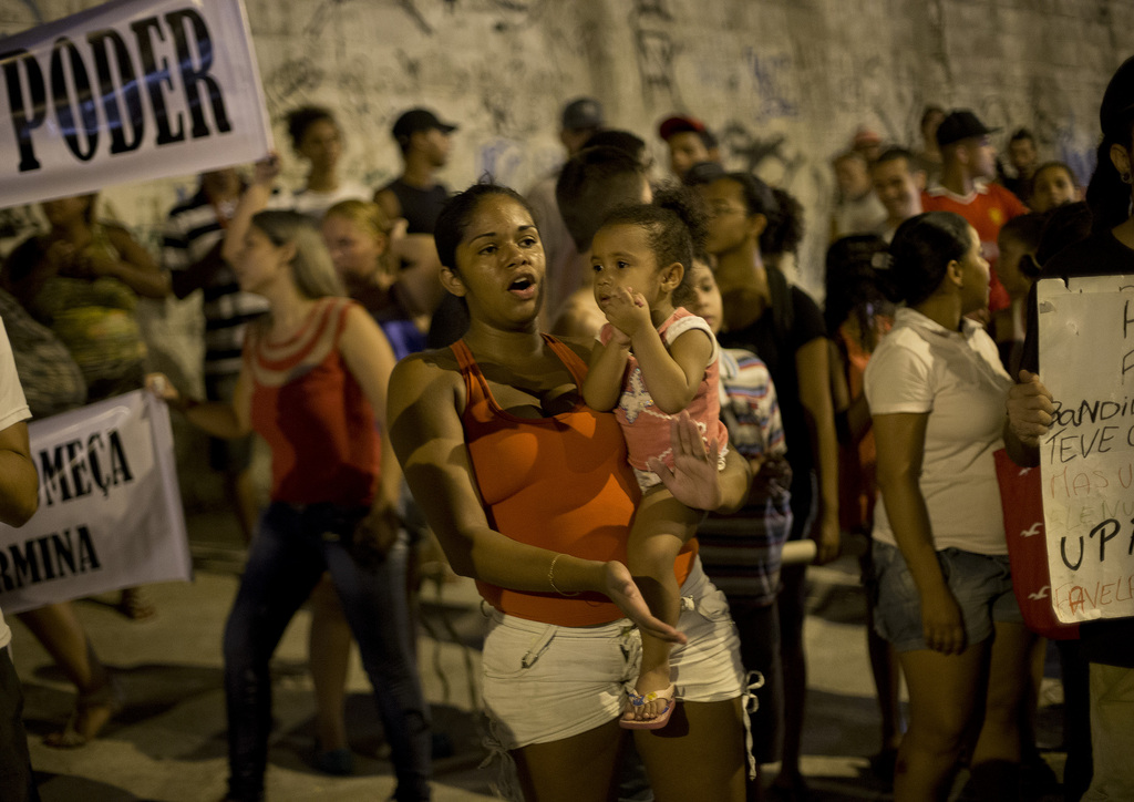 A woman carries a baby as she shouts slogans against violence by security forces during a protest at the Mare slum, in Rio de Janeiro, Brazil, Monday, Feb. 23, 2015. Mare is one of several impoverished areas in Rio where police or soldiers have tried to push out gangs and set up permanent posts as part of efforts to make Rio safer ahead of the 2016 Olympics. But many residents complain of heavy-handed tactics by police. (AP Photo/Silvia Izquierdo)