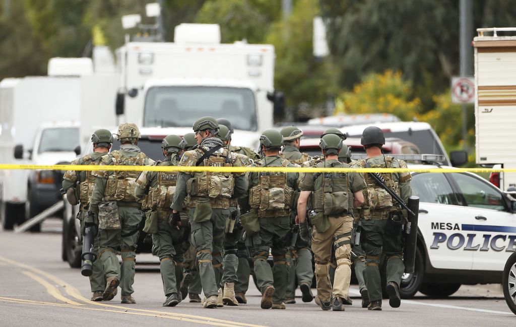 A SWAT team walks down the street near Adams Elementary School searching for a gunman on Wednesday, March 18, 2015 in Mesa, Ariz. A gunman wounded at least four people across multiple locations in the Phoenix suburb. The first shooting happened at a motel, and people were also wounded at a restaurant and nearby apartment complexes.  (AP Photo/The Arizona Republic, Rob Schumacher)  MARICOPA COUNTY OUT; MAGS OUT; NO SALES