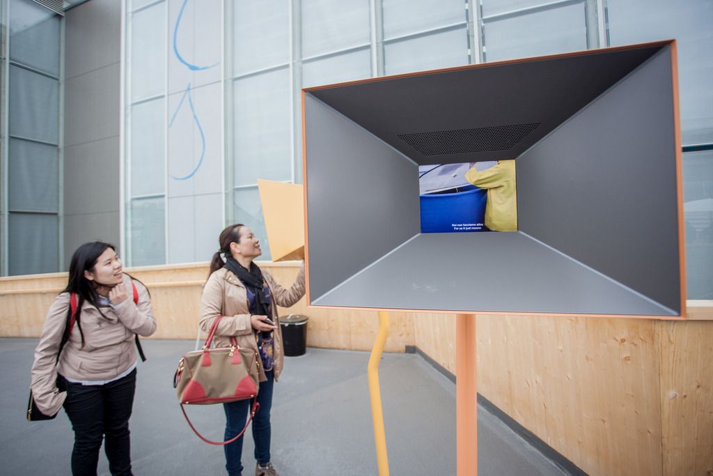 Visitors watch a monitor outside the entrance of the Swiss Pavilion, seen on the opening day of the Milan Expo 2015, in Milan, Italy, Friday, 01 May 2015. The Swiss Pavilion is built with four towers filled with food (salt, coffee, water, apple rings). The six-month Expo Milano 2015 will run until October 31 and is expected during the coming months to attract 20 million visitors. Some 140 countries, the United Nations and the European Union will have displays at Expo. (KEYSTONE/Ti-Press/Pablo Gianinazzi)