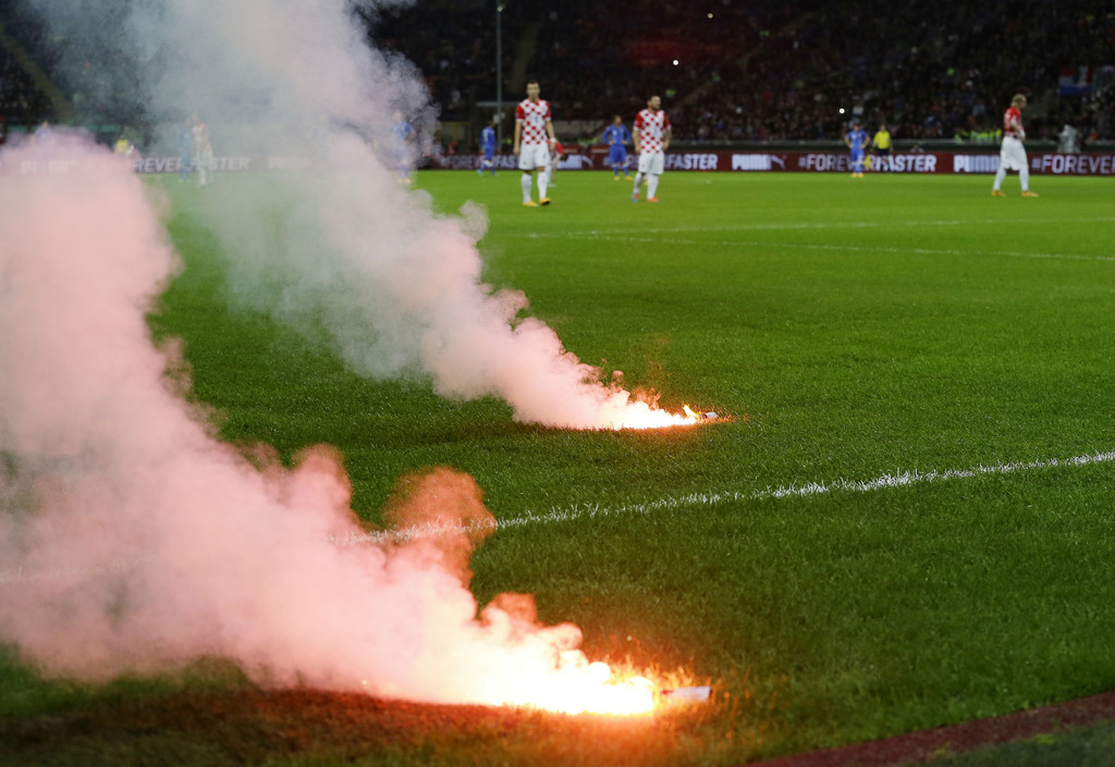 Flares thrown by supporters burn on the field of play during the Euro 2016 qualifying soccer match between Italy and Croatia, at the San Siro stadium in Milan, Italy, Sunday, Nov. 16, 2014. (AP Photo/Antonio Calanni)