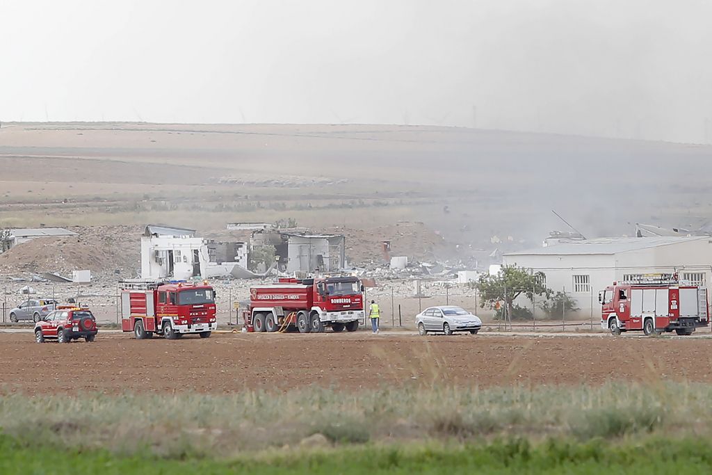 The destroyed fireworks factory Pirotecnia Zaragozana's building is seen behind firefighters trucks after a huge explosion occurred   in Pinseque, Spain, Monday, Aug. 31, 2015. The blast at a fireworks factory in northeastern Spain killed a number of people and seriously injured tothers, police and firefighters didn't know the cause of the blast. (AP Photo/Aranzazu Navarro)