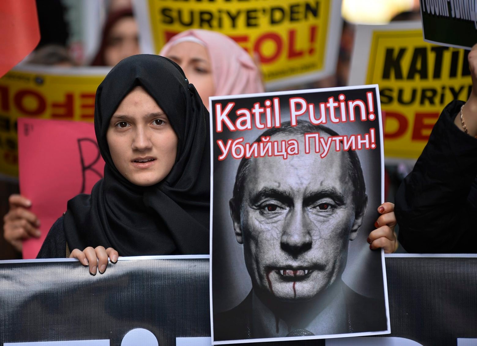 A demonstrator holds a picture depicting Russian President Vladimir Putin during a protest against Russian military operations in Syria, in Istanbul, Turkey, Saturday, Oct. 3, 2015. The picture reads both in Turkish and Russian: 'Murderer Putin'. In ramping up its military involvement in Syria's civil war, Russia appears to be betting that the West, horrified by Islamic State's atrocities, may be willing to tolerate Syrian President Bashar Assad for a while, perhaps as part of a transition. (AP Photo) Turkey Russia Syria