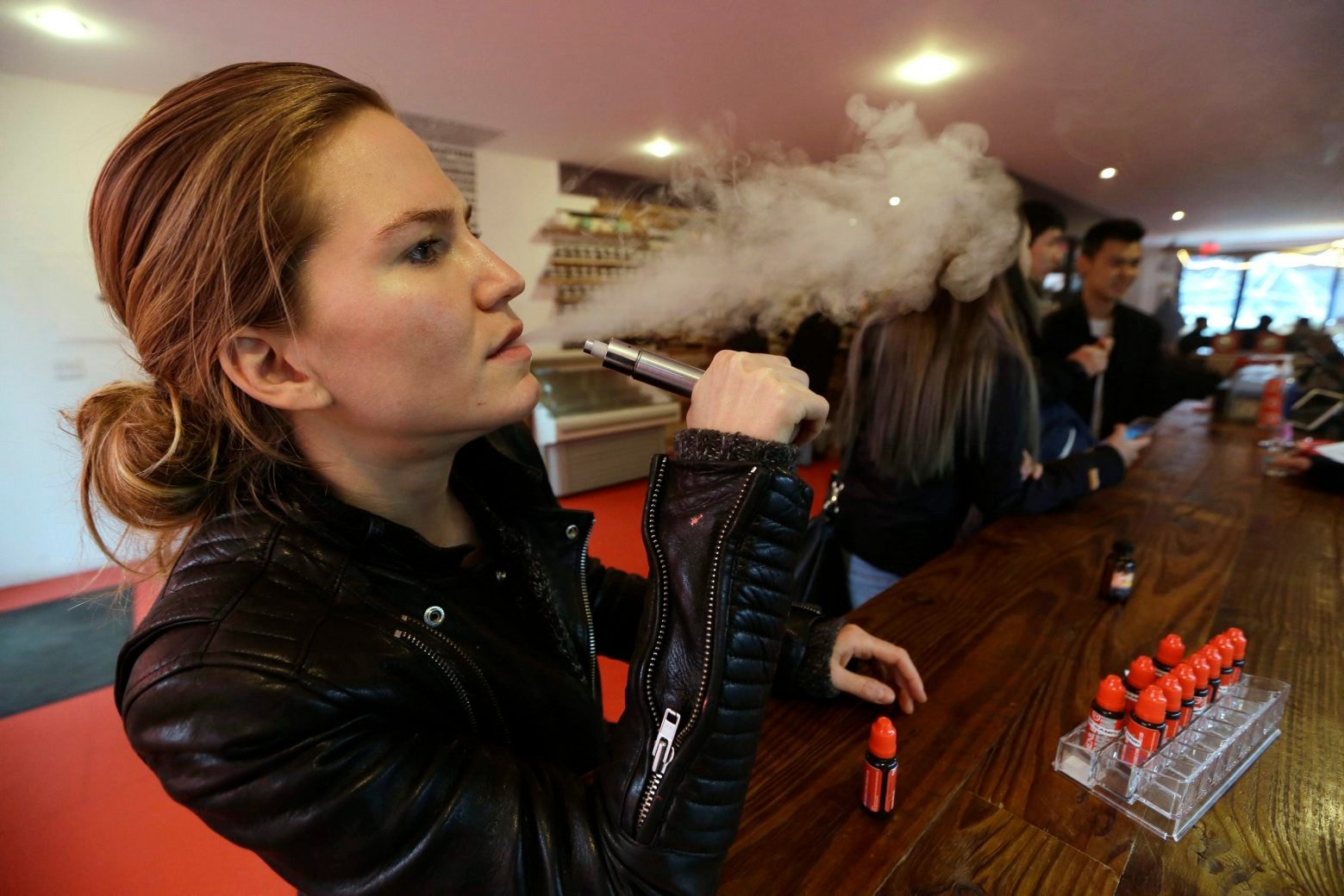 FILE - In this Feb. 20, 2014 photo, Talia Eisenberg, co-founder of the Henley Vaporium, uses her vaping device in New York. Soon, the Food and Drug Administration will propose rules for e-cigarettes. The rules will have big implications for a fast-growing industry and its legions of customers.  (AP Photo/Frank Franklin II, File) FDA-Electronic Cigarettes