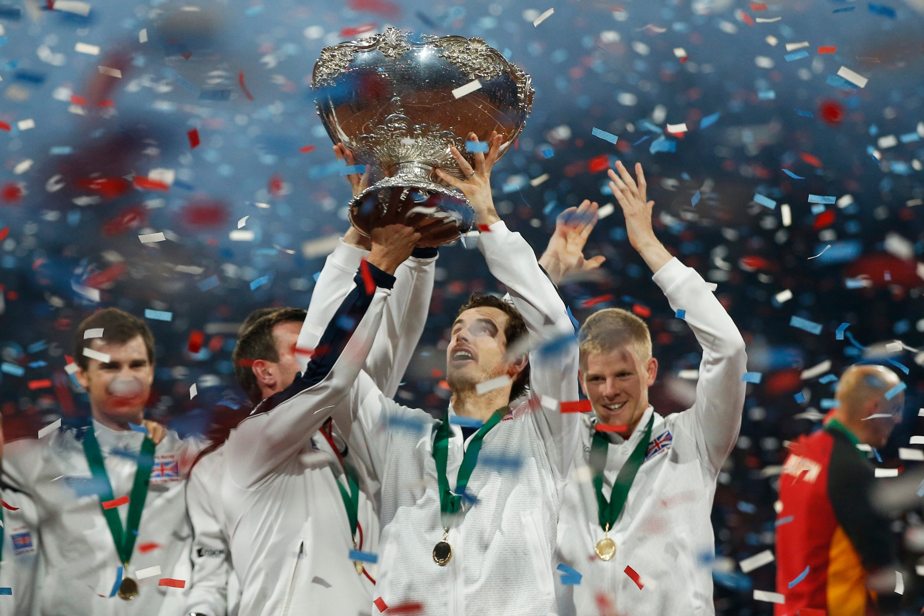 Britain's Andy Murray, center, takes over the Davis Cup from Britains captain Leon Smith, left, as the team celebrates after Andy Murray defeated Belgiums David Goffin in three sets, 6-3, 7-5, 6-3, during their singles Davis Cup final tennis match at the Flanders Expo in Ghent, Belgium, Sunday, Nov. 29, 2015. (AP Photo/Alastair Grant) APTOPIX Belgium Britain Davis Cup Final Tennis