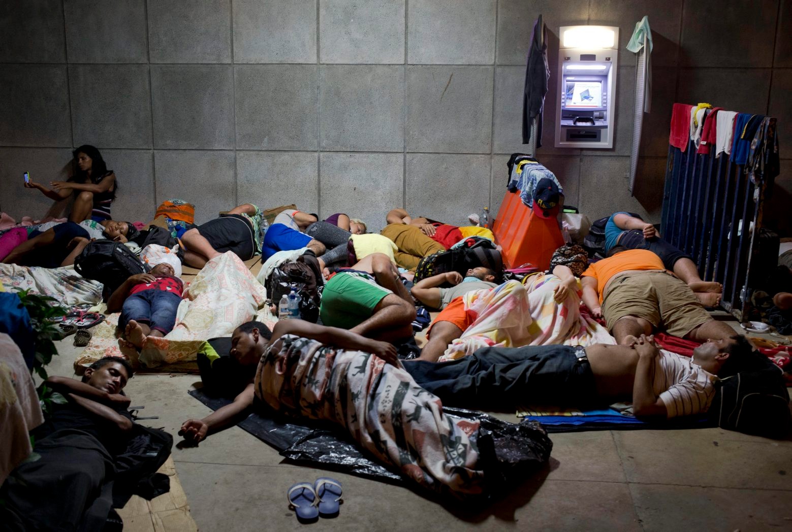 FILE - In this Nov. 21, 2015 file photo, a Cuban woman migrant uses her cell phone while other Cubans sleep, outside of the border control building in Penas Blancas, Costa Rica, on the border with Nicaragua which closed its borders to Cuban migrants. The Costa Rican Foreign Ministry said in a Dec. 28 statement that the first humanitarian transfer will airlift the Cuban migrants from that country to El Salvador in January. From there they will continue by bus toward Mexico. The number of Cubans stranded in Costa Rica has reached at least 8,000 since neighboring Nicaragua closed its border to them weeks ago.  (AP Photo/Esteban Felix, File) Costa Rica Cuba Migrants