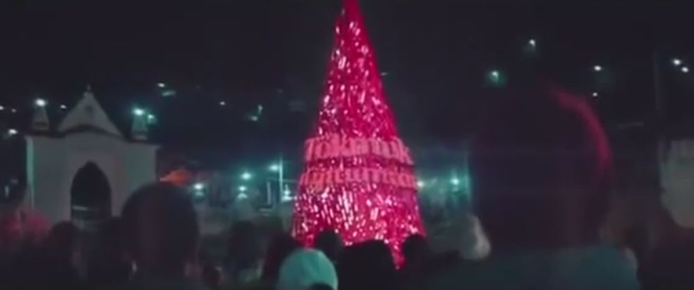 Le groupe de jeunes construit un arbre de Noël, fait à l'aide de capsules aux couleurs de Coca-Cola, sous le slogan "restons unis".